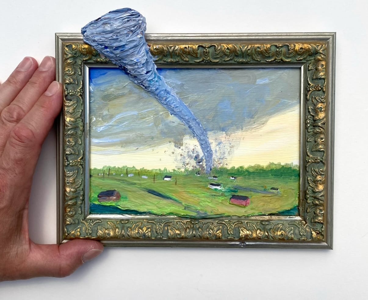 a small picture frame depicting a landscape with a tornado. the funnel cloud protrudes from outside of the frame