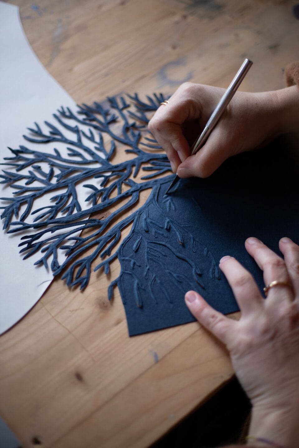 a detail of an artist's hands working on cut material in the shape of coral