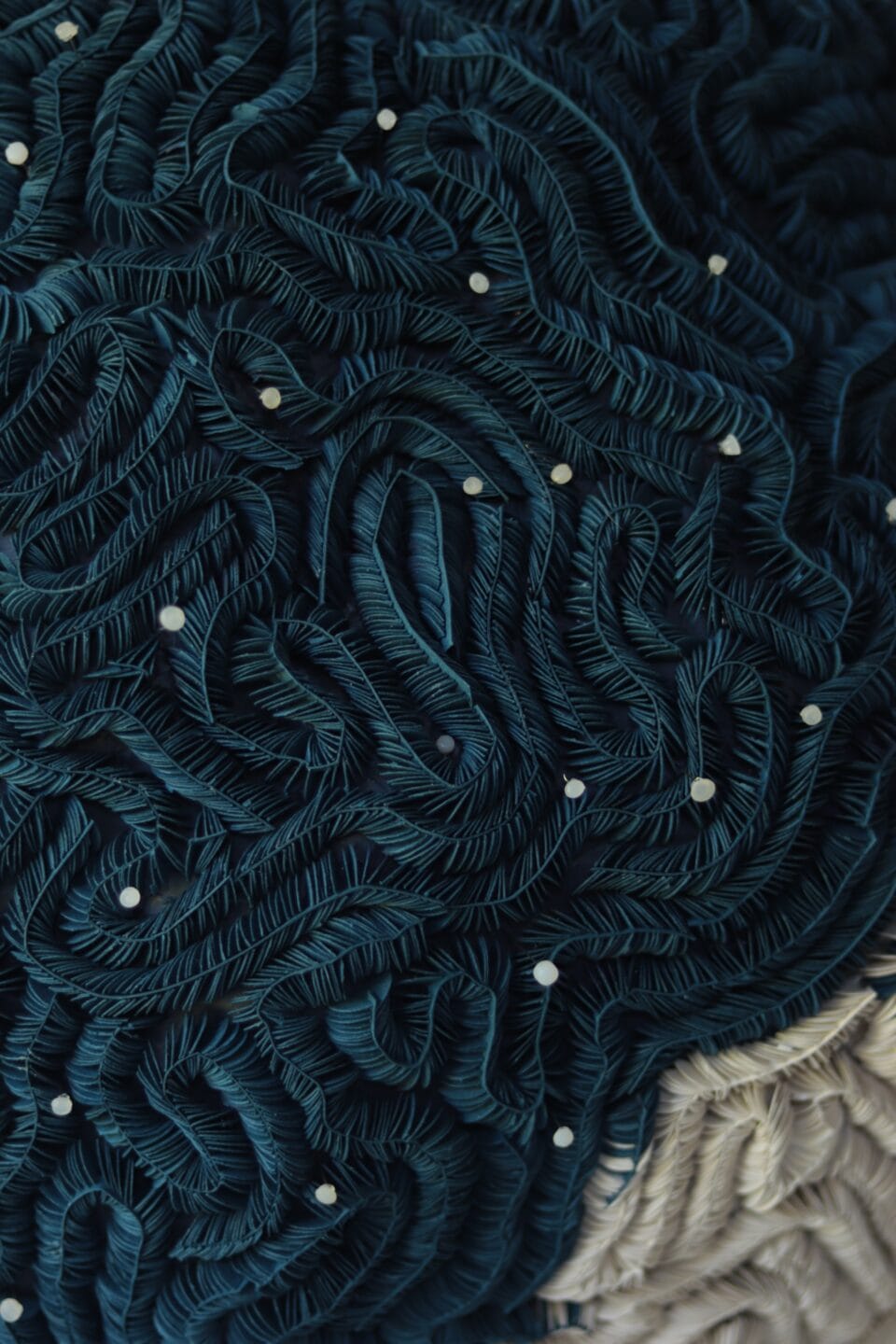 a detail of an abstract, dark blue, textured sculpture