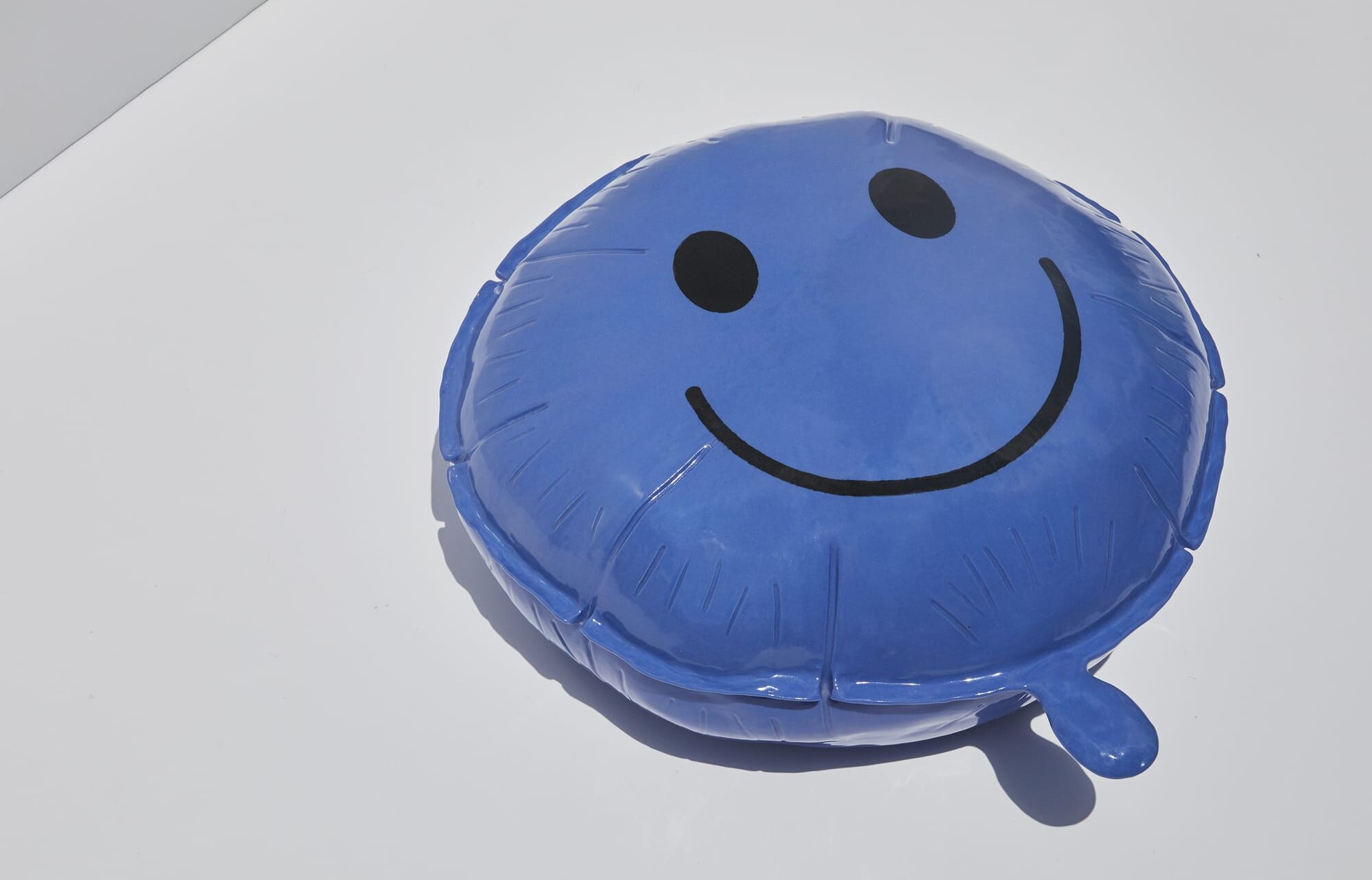 a ceramic sculpture of a blue happy face balloon