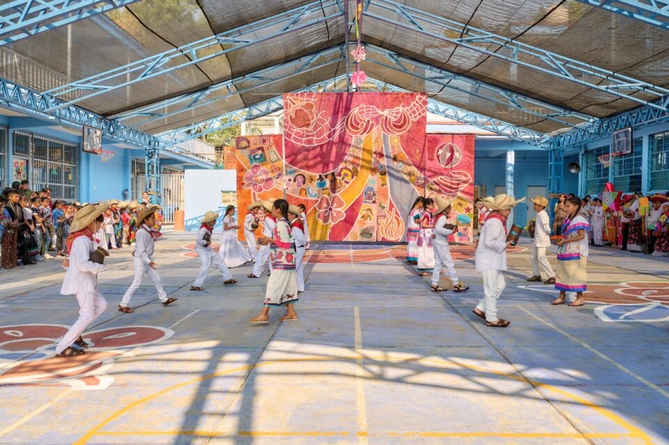 children dance in front of a three panel installation in a large warehouse like space 