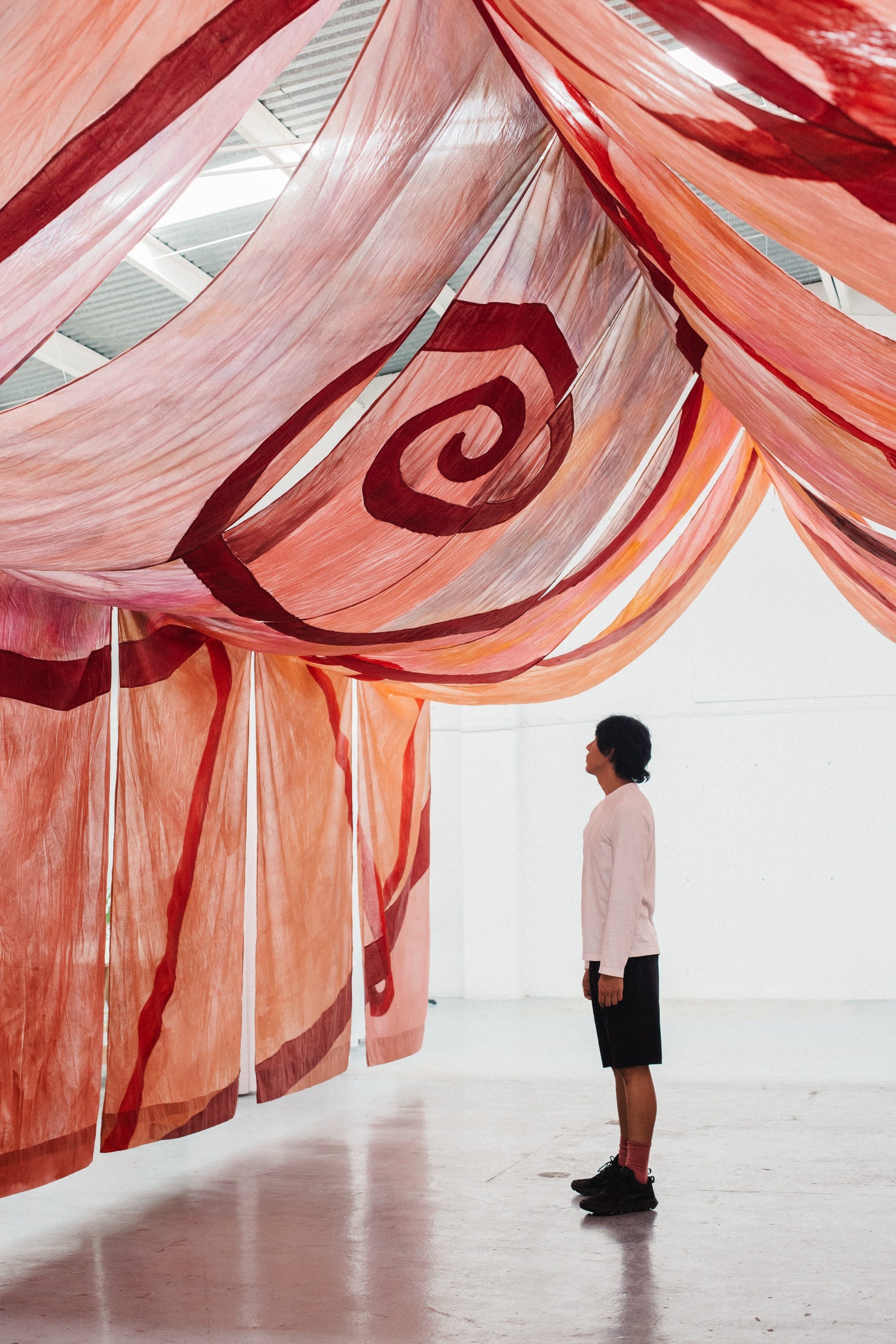 a person stands beneath a canopy of pink fabric
