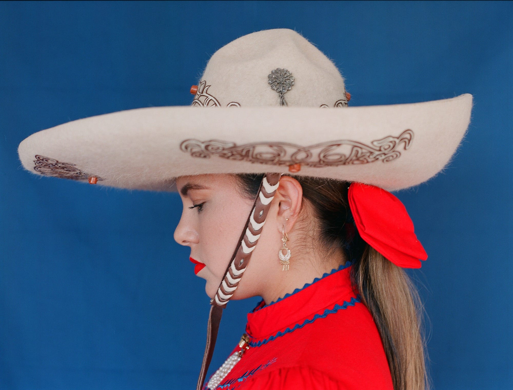 a portrait of a young woman in profile, wearing a wide-brimmed hat and a red shirt