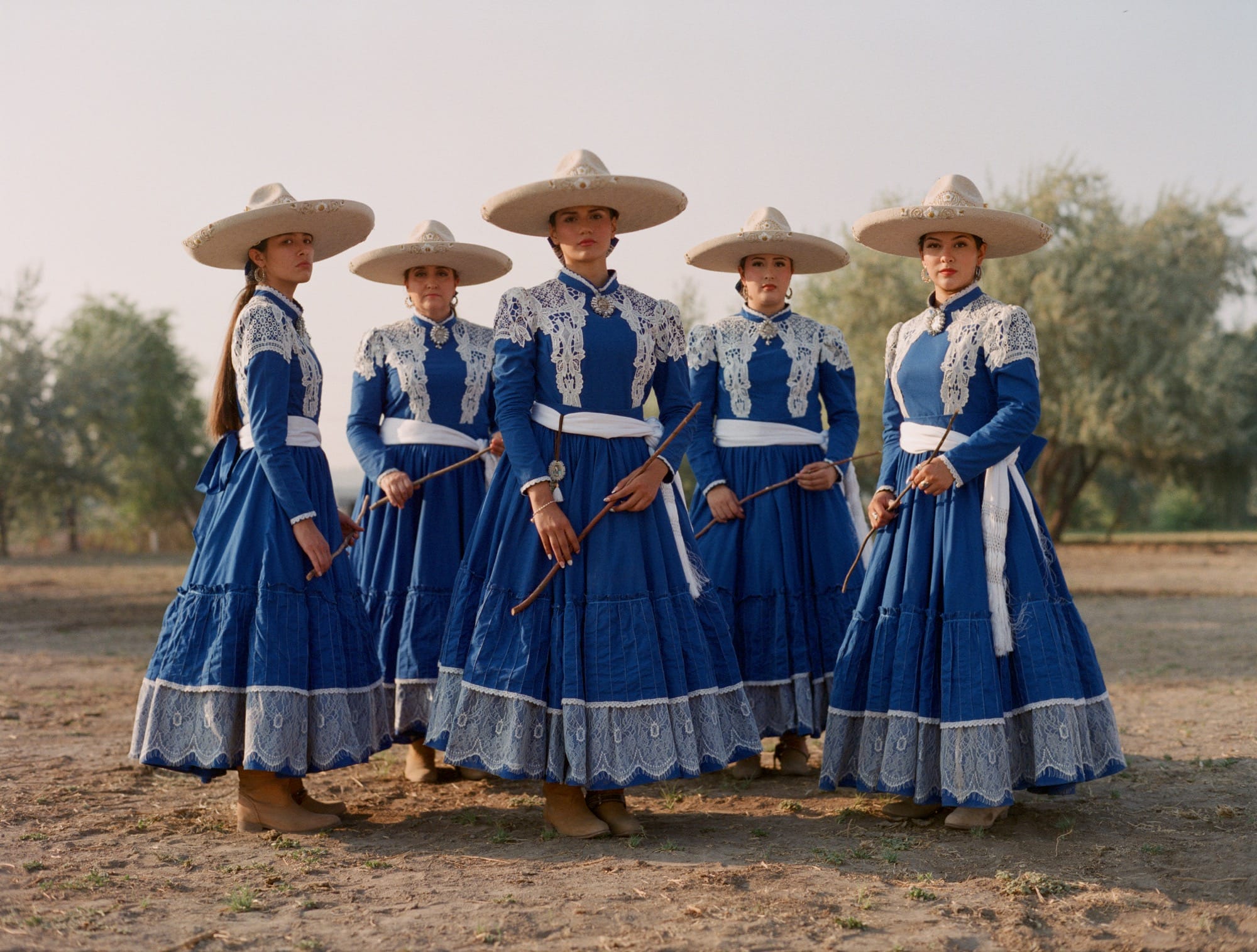 a portrait of five women wearing blue-and-white dresses and wide-brimmed hats