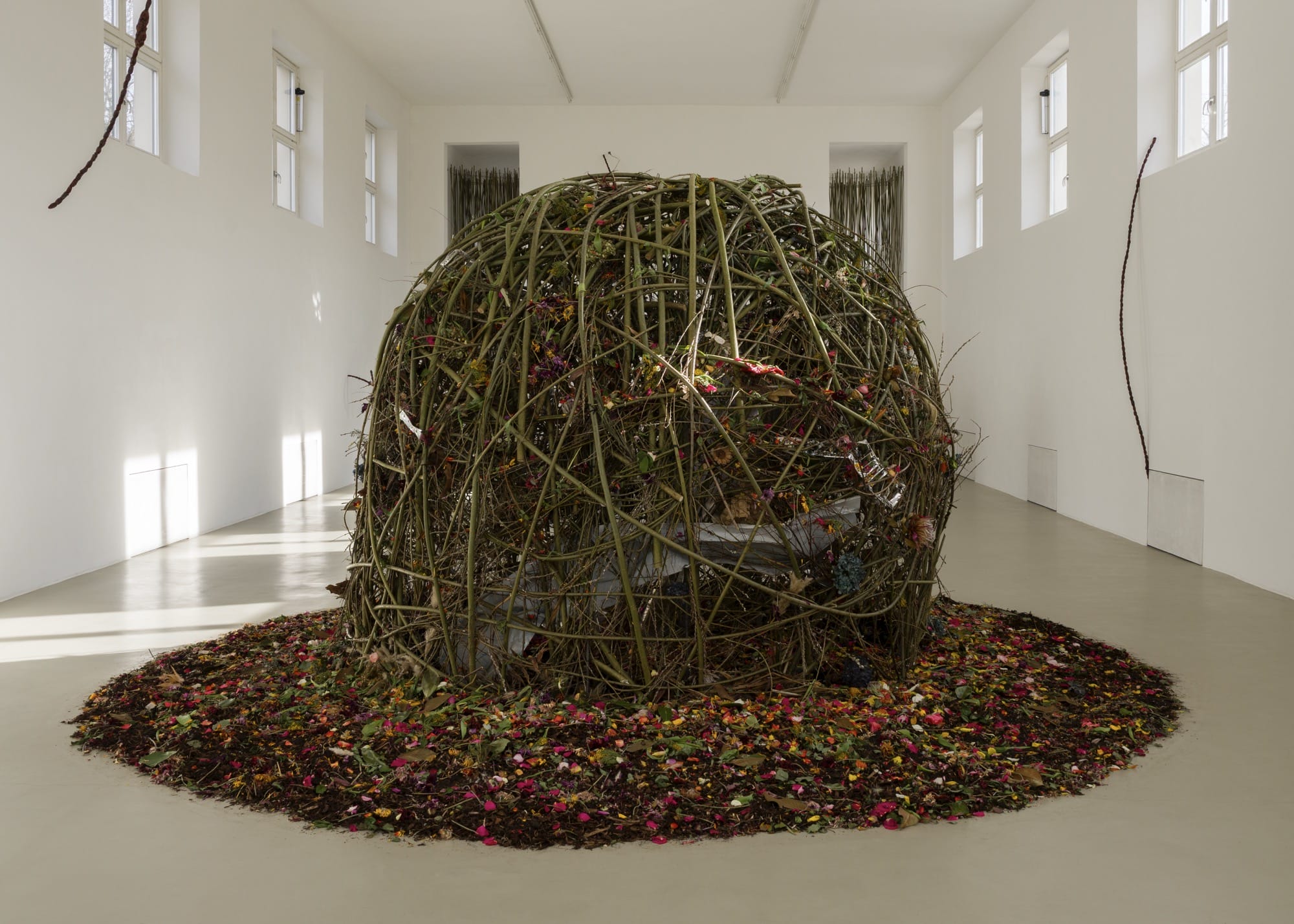 a large orb-like installation made of flowers with a pool of soil and flowers below