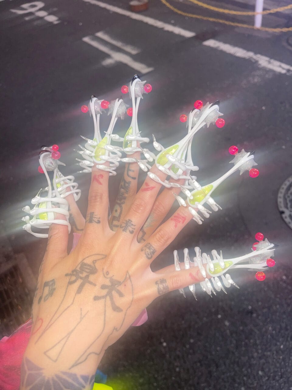 a long manicure with white, green, and pink sculptural elements