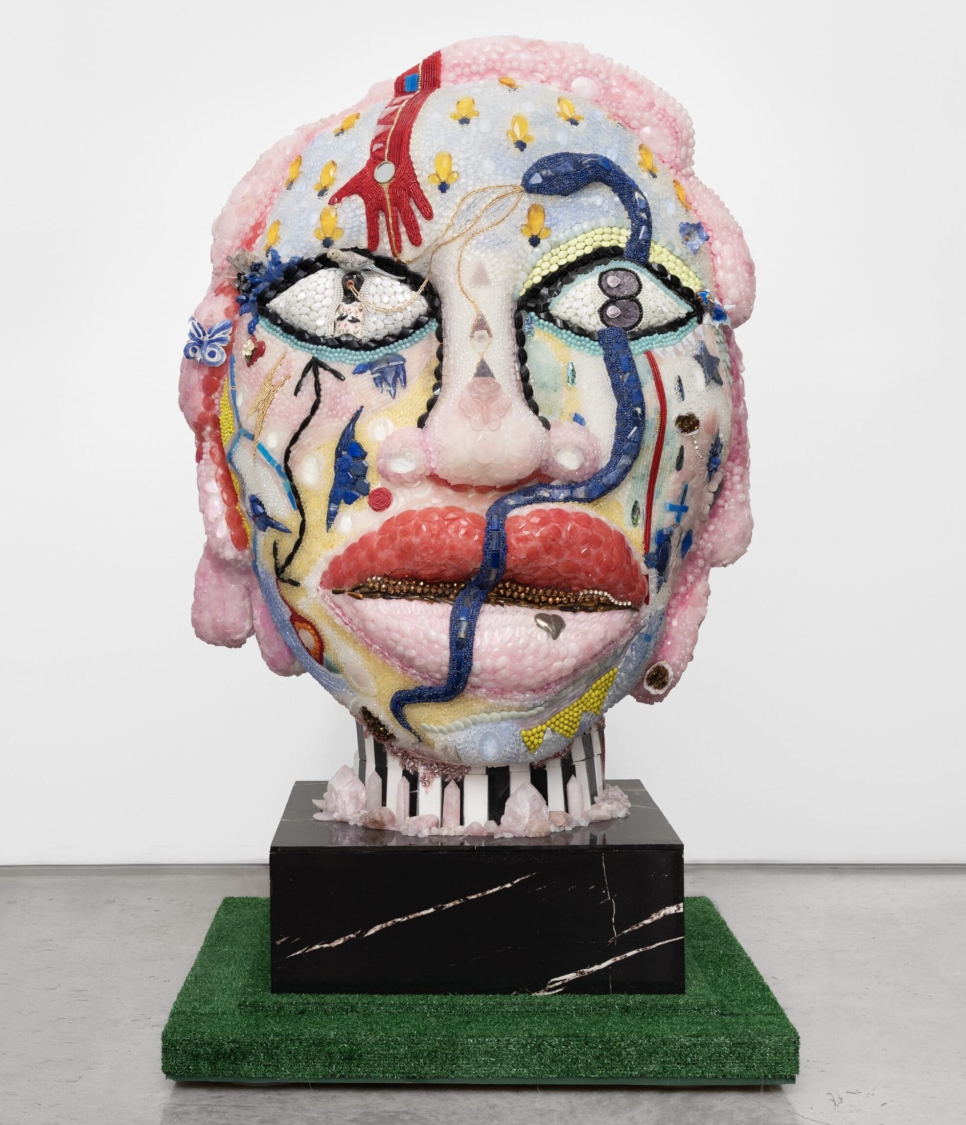 a large mixed-media sculpture of a head coated with beads and other materials
