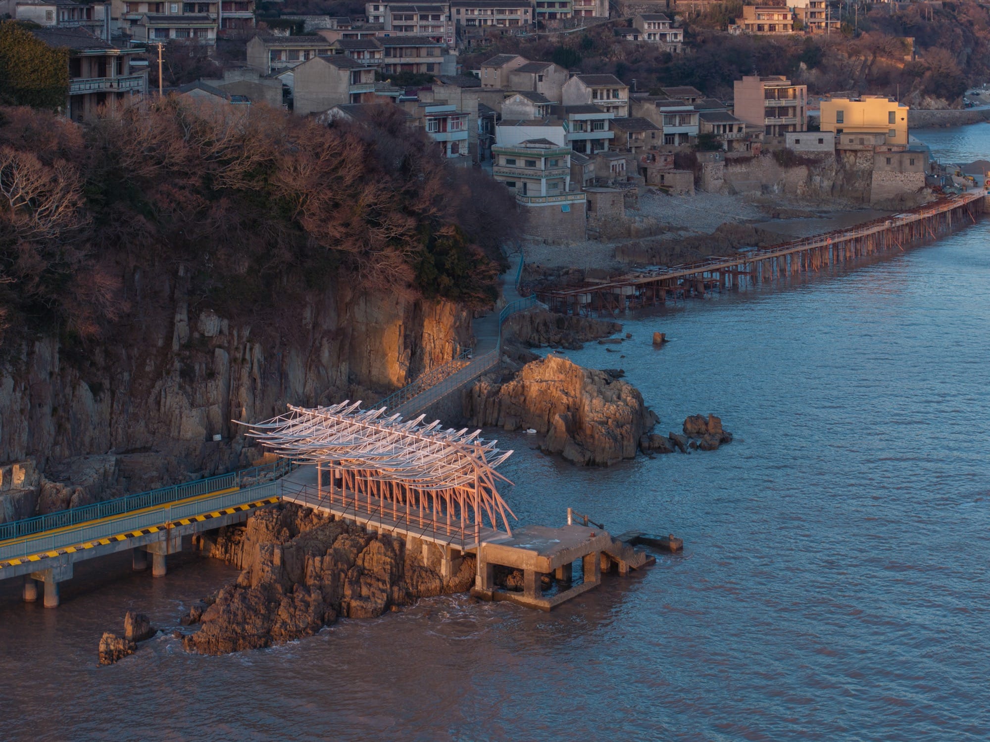 an aerial view of a seaside pavilion made of white feather-like blades