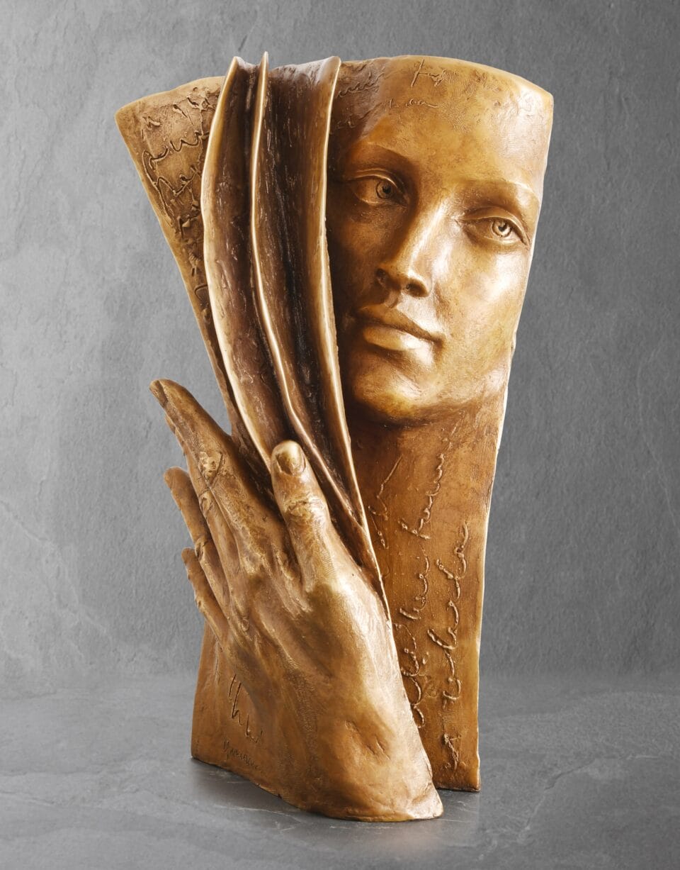 a sculpture of a woman's face and hand merging with the pages of a book or manuscript