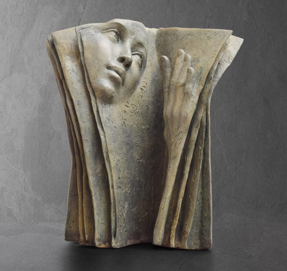 a sculpture of a book with a face in relief on the left page