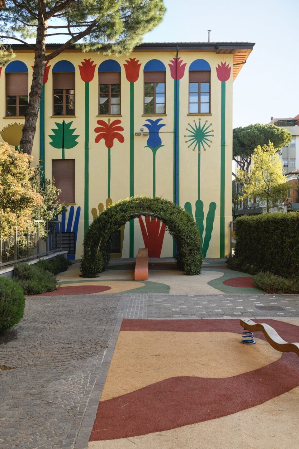 a detail of a building covered entirely in a colorful, geometric mural with a light yellow background and green, blue, and red patterns