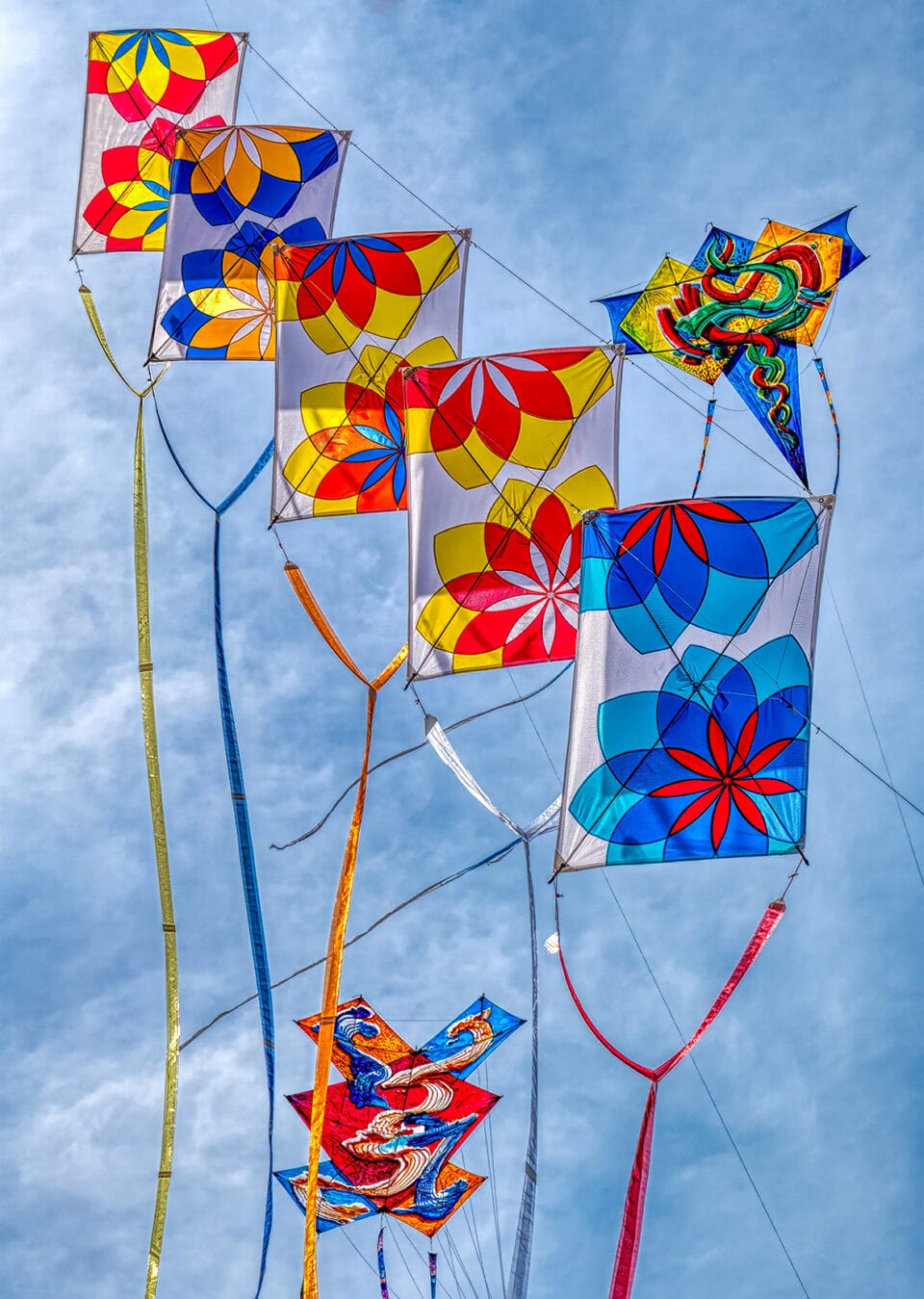 a series of vibrant patterned kites in the sky