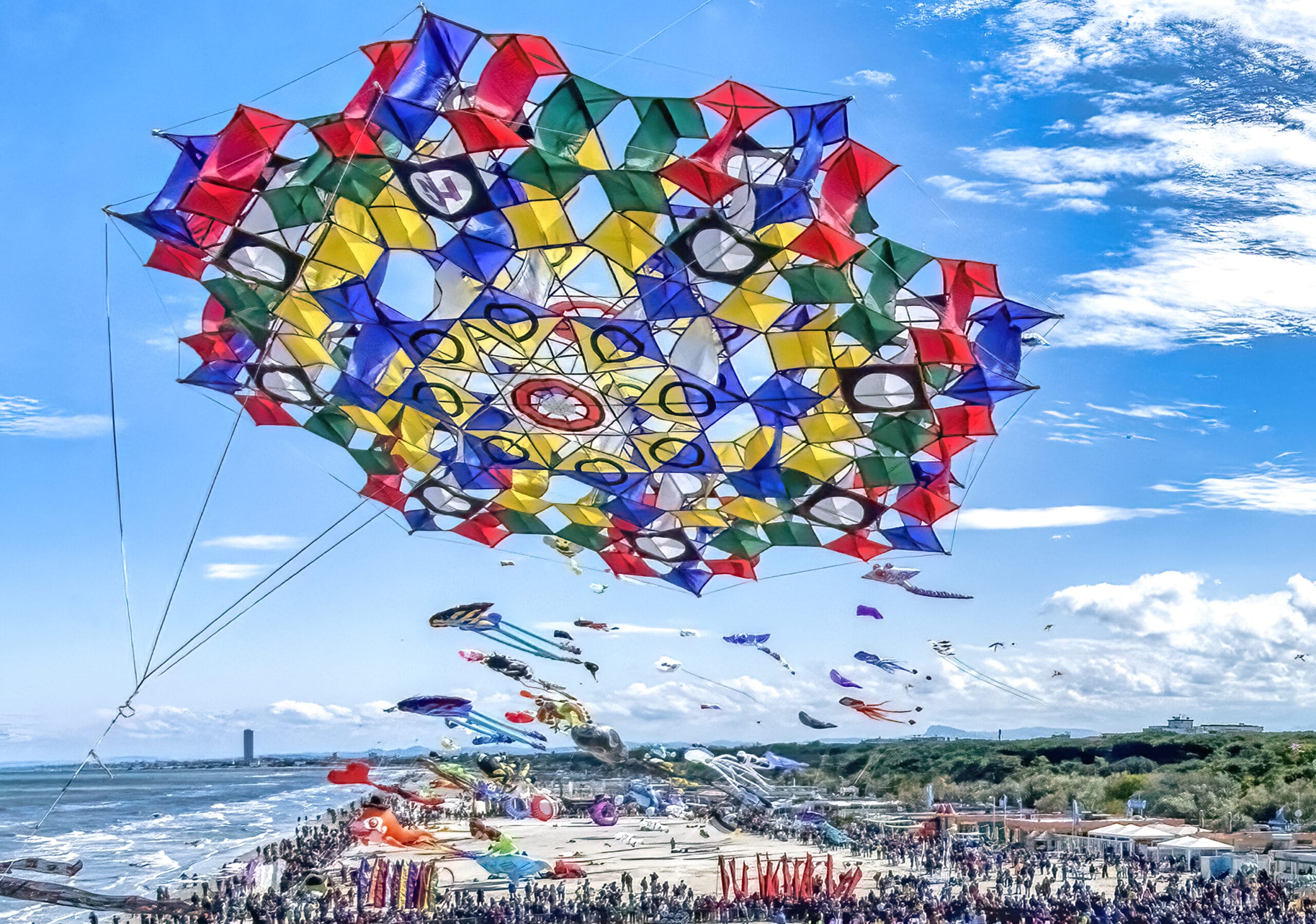a massive vibrant kite in the sky above a beach