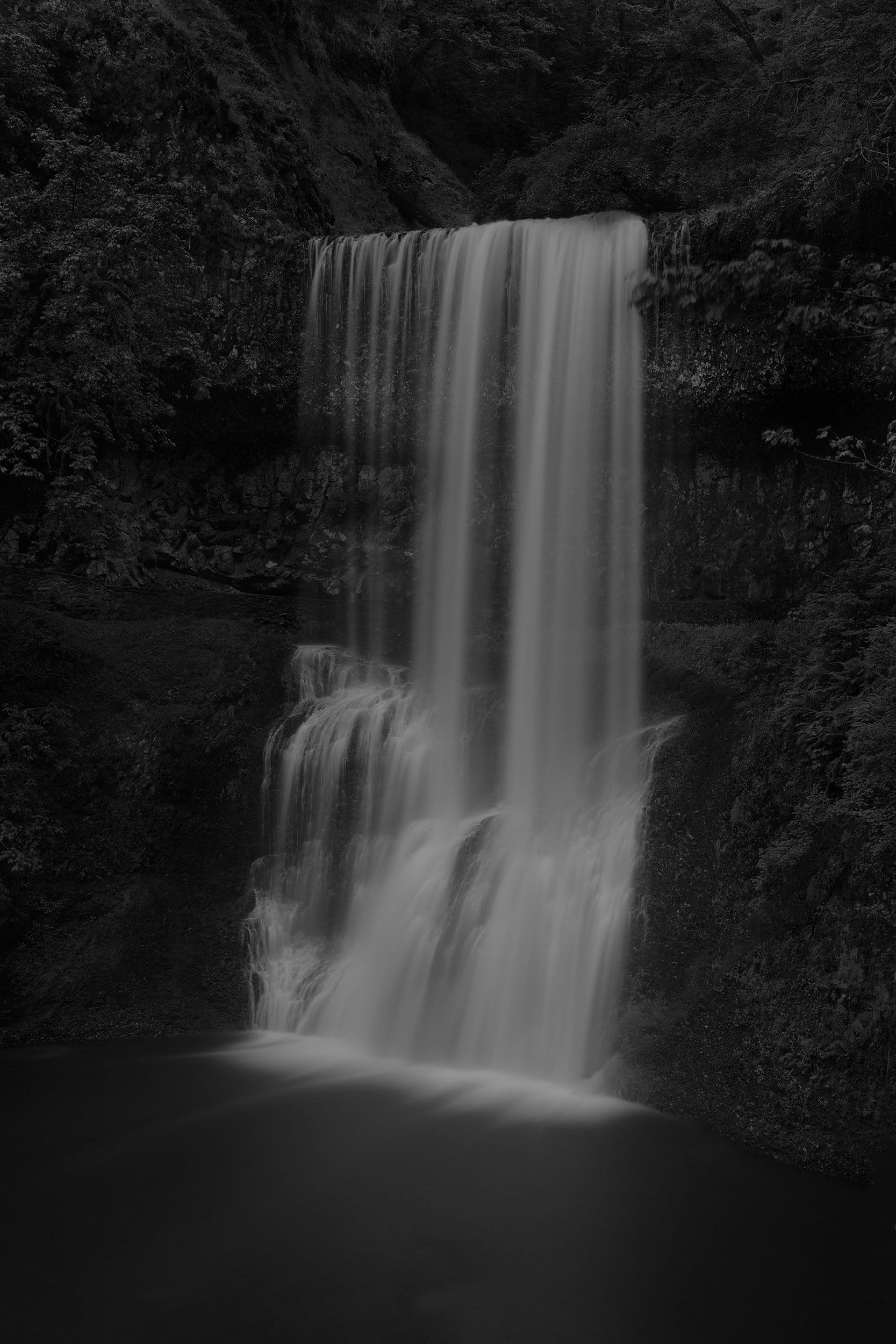 a moody black and white image of a waterfall