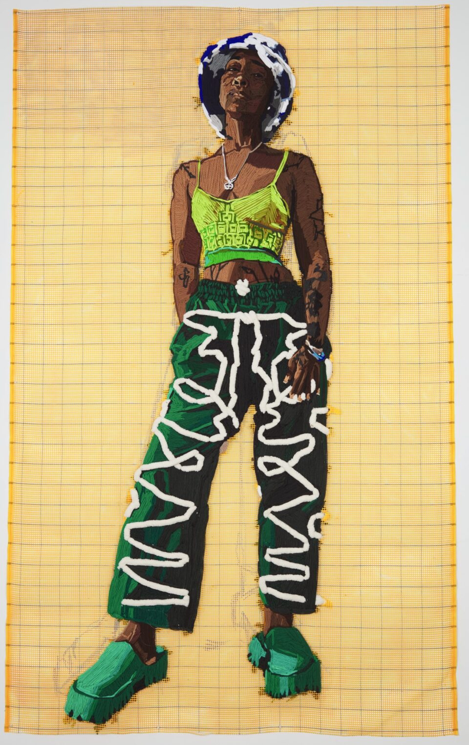 a large-scale embroidered portrait of a vibrantly-dressed Black woman against a yellow gridded background