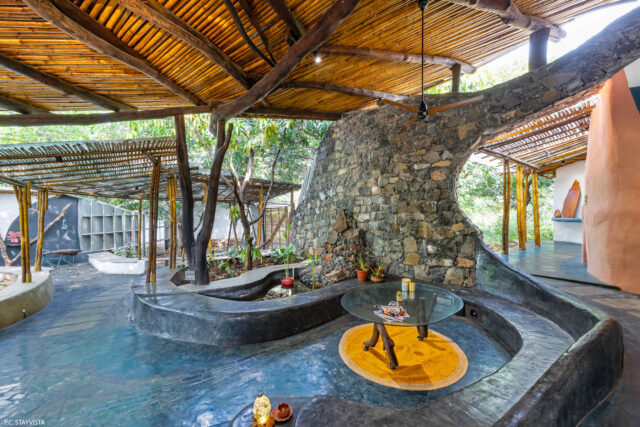 the interior of a biophilic residential design, with wood-beamed ceilings, organic walls, and earthy floors