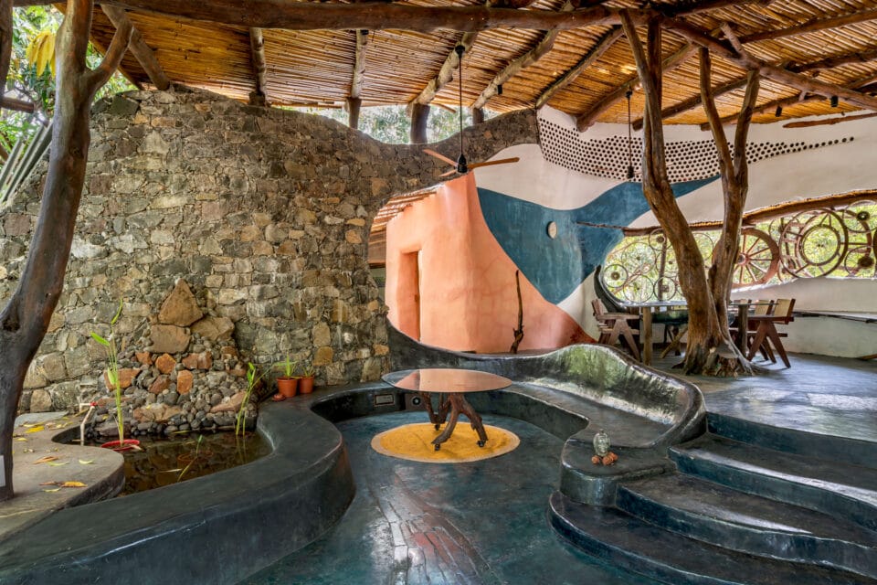 the interior of a biophilic residential design, with wood-beamed ceilings, organic walls, and earthy floors