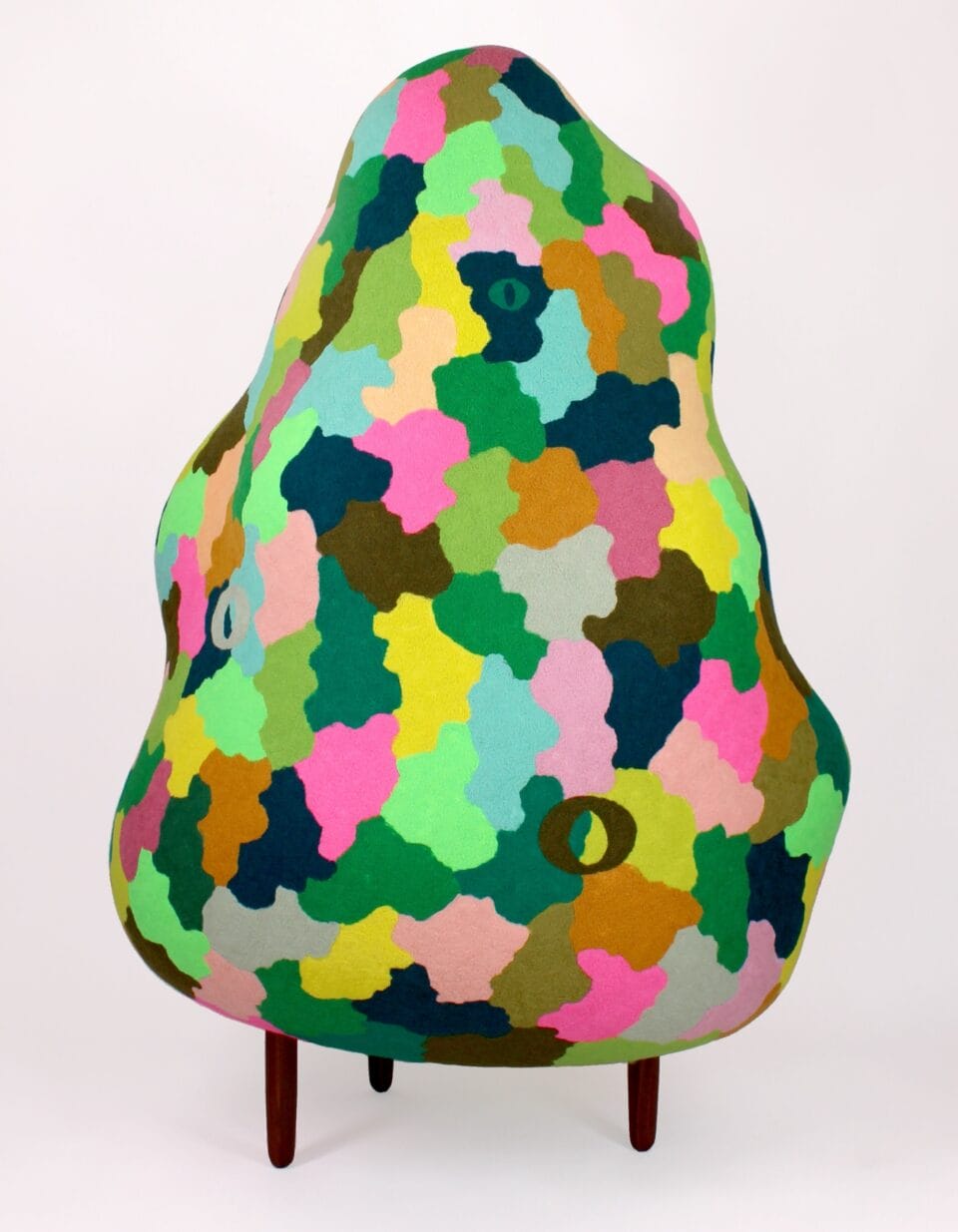 a cloud-like, abstract sculpture on spindly legs with a colorful pattern and a single eye