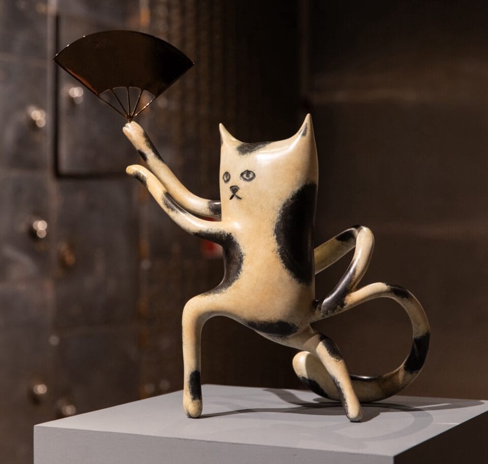 a sculpture of a cartoonish cat waving a fan
