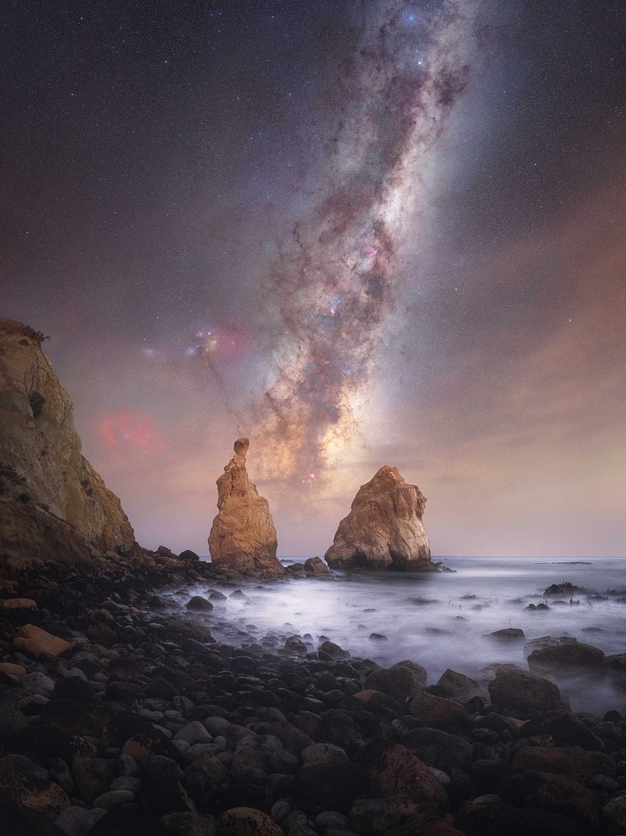 the milky way above a rocky sea cove