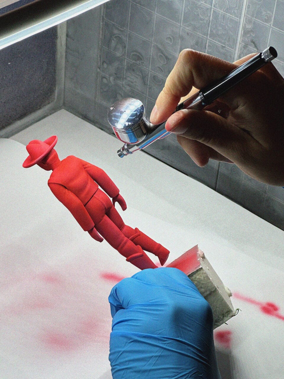 a hand airbrushing a giant red cowboy