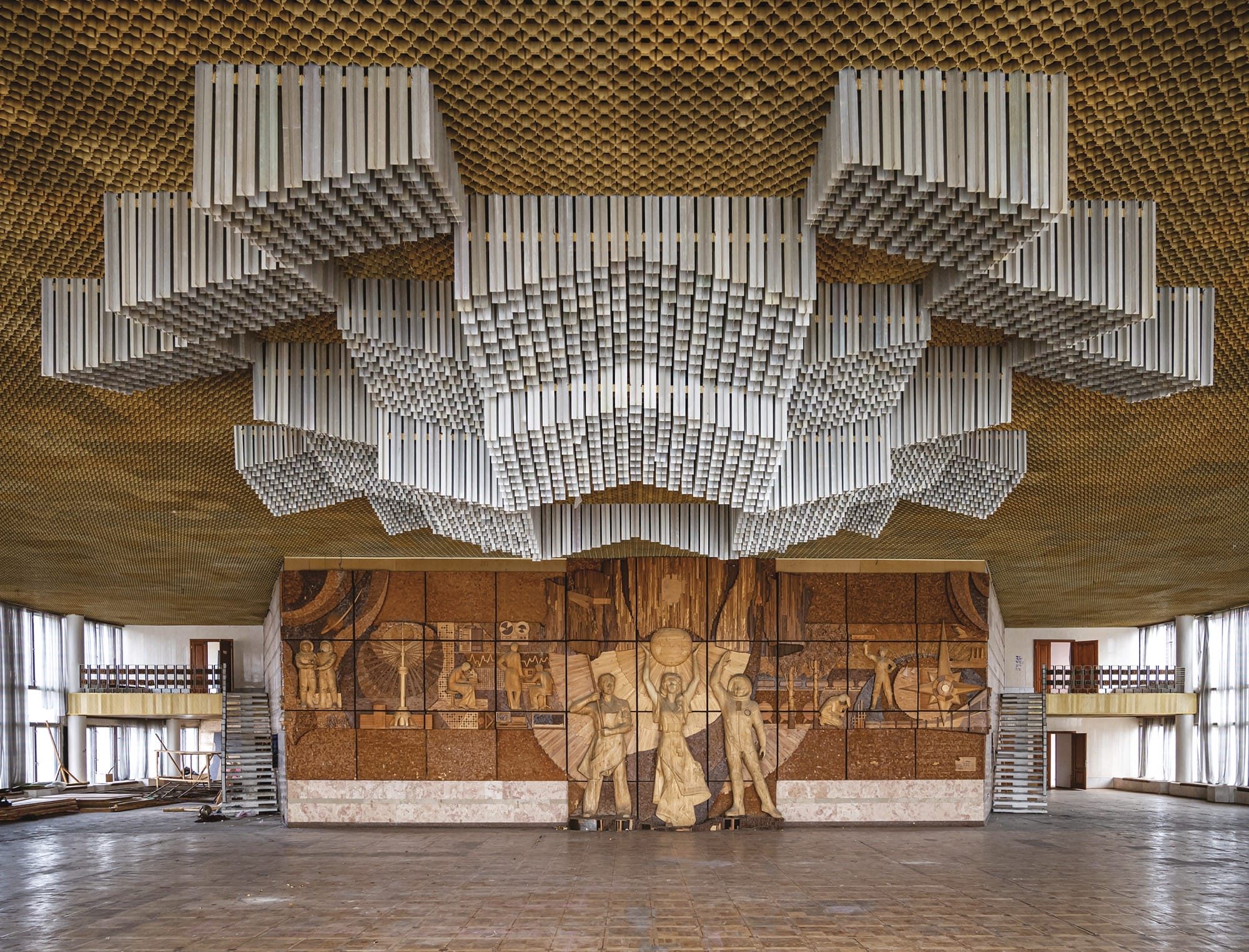 a silver installation hangs from the ceiling with a wood mural in the back