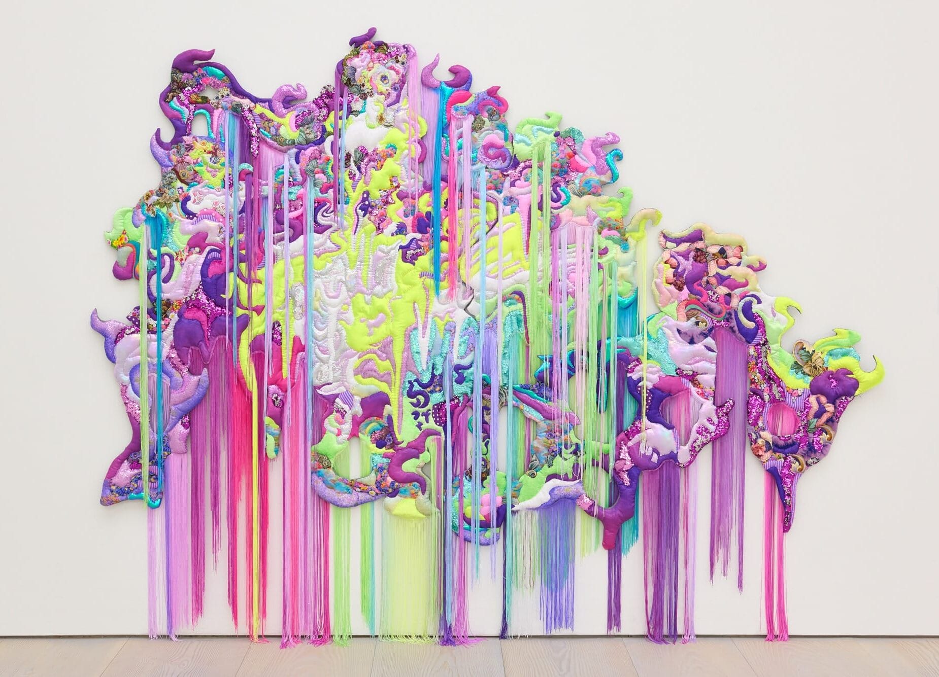 a monumental, abstract wall installation that appears to be cascading or bleeding a range of neon colors, as if the medium has been thrown at the wall and it is dripping down to the floor