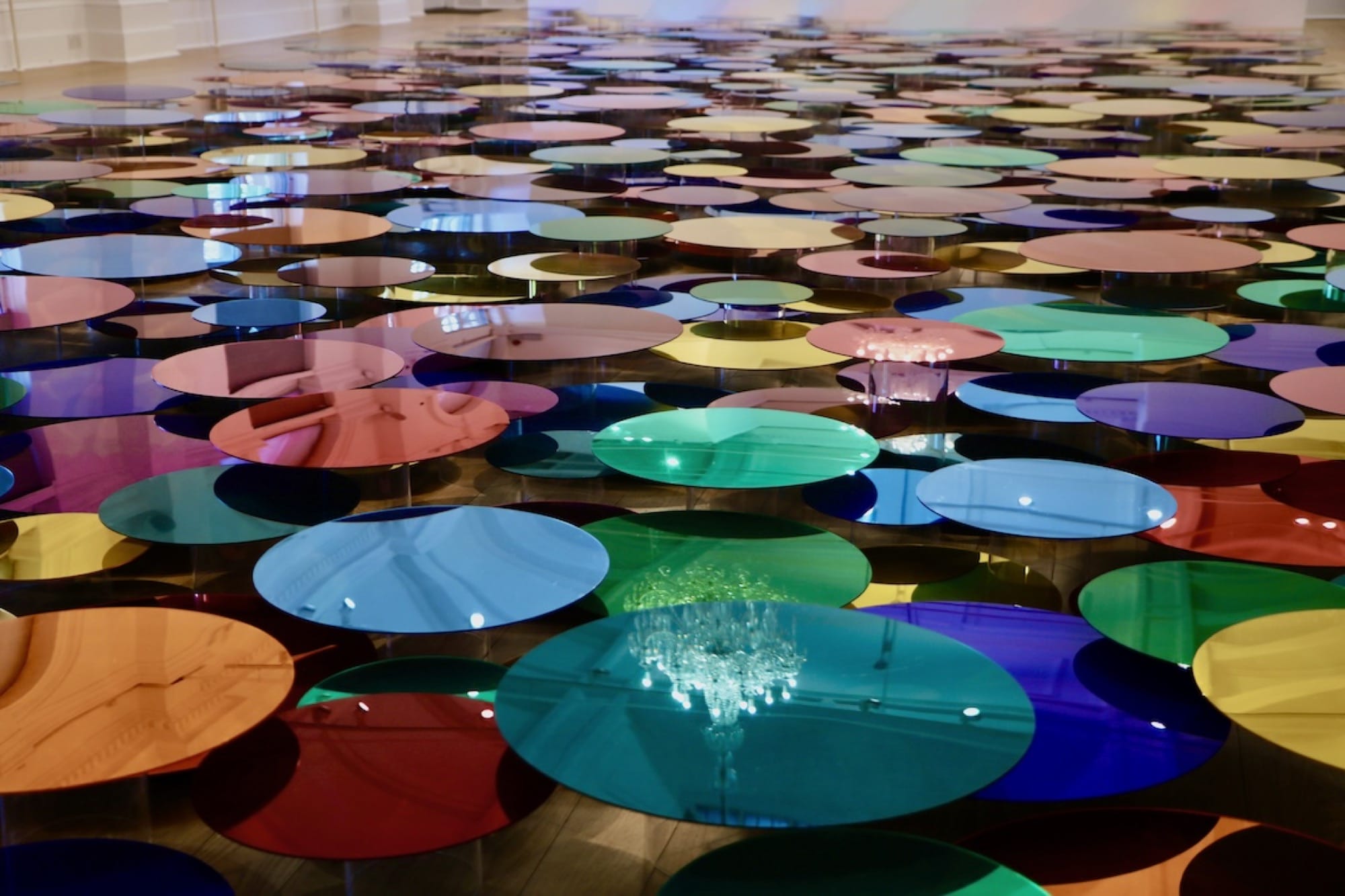 a floor installation of numerous shiny, colorful circles